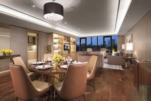 A modern hotel room with a dining area, a living area with a sofa and armchairs, a TV, and a large window with a city view. - Ascott Heng Shan Shanghai (Shanghai)