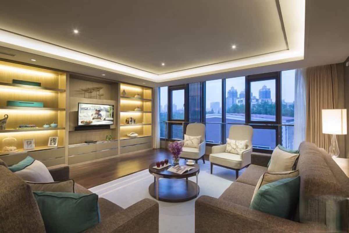 A modern living room with a flat-screen TV, comfortable seating, and a city view.