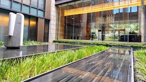 A modern building with large glass windows, a reflective water feature, and a well-maintained lawn. - Ascott Heng Shan Shanghai (Shanghai)