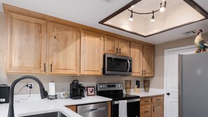 Eine moderne Küche mit Holzschränken, einer Mikrowelle, einer Kaffeemaschine und einem Kühlschrank.