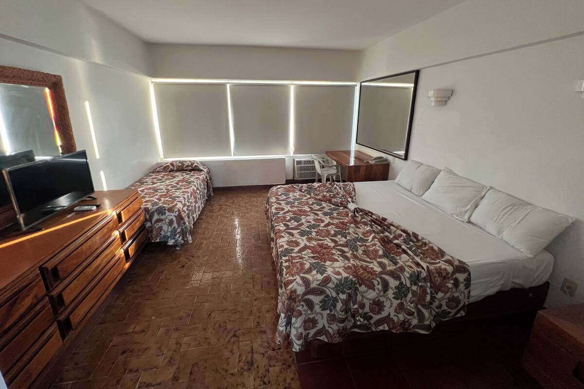 A hotel room with two beds, a TV, a desk, and a chair.