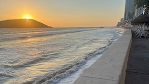 A beach with a sunset, waves, and a paved walkway. - Islas del Sol (Mazatlán)