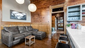 Un salon accueillant avec un canapé en cuir, une petite table en bois et un coin bar équipé de tabourets.