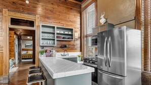 Une cuisine moderne dotée d’un îlot central, d’appareils électroménagers en acier inoxydable, de meubles de rangement en bois et donnant sur la salle à manger.