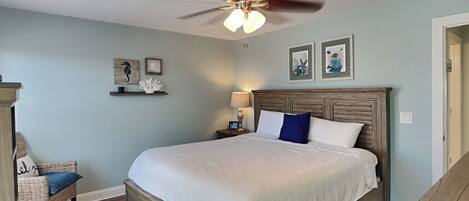 A bedroom with a wooden bed, a ceiling fan, and wall-mounted artwork.