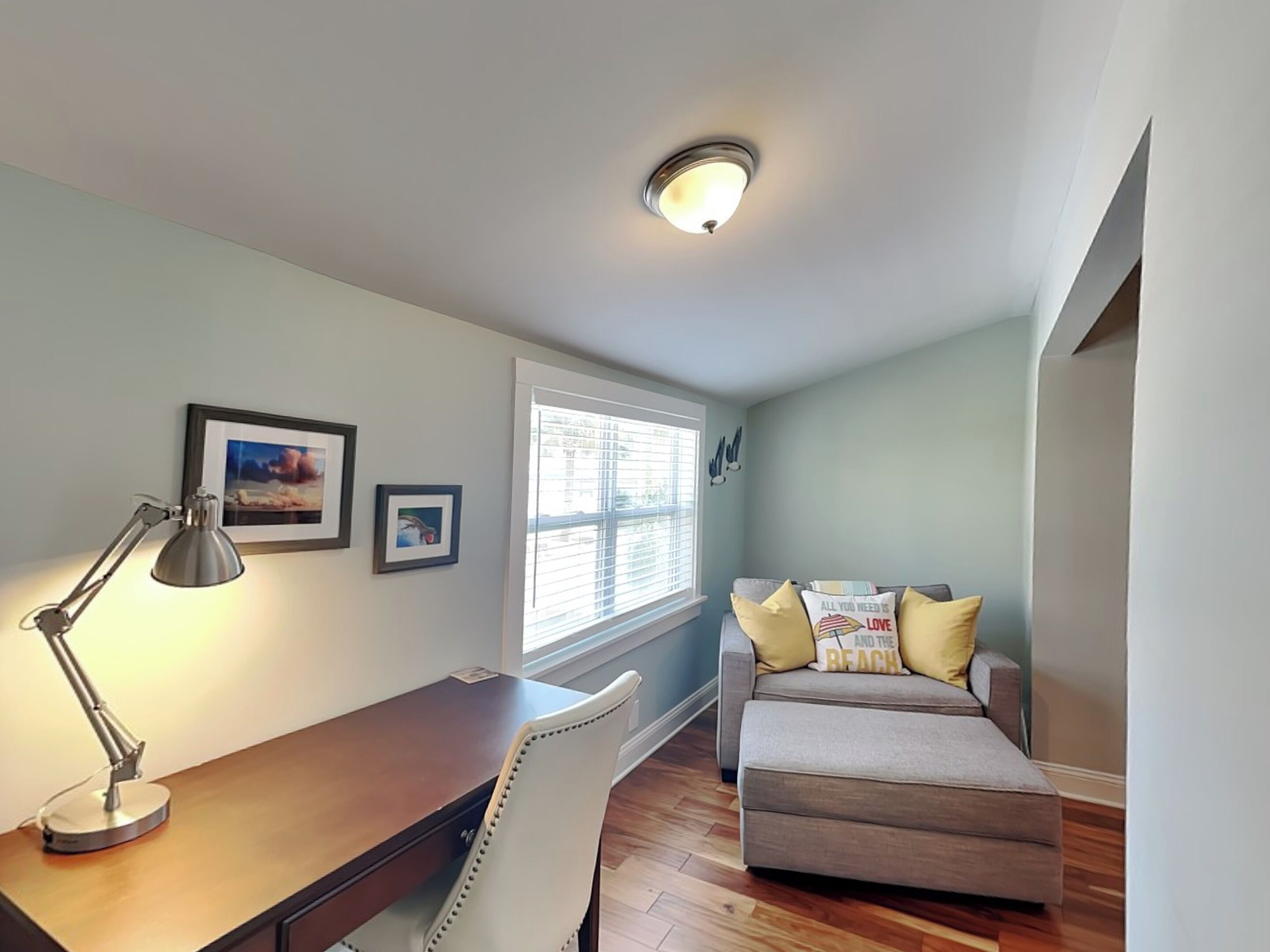 Una habitación acogedora con escritorio, silla y sofá con cojines decorativos.