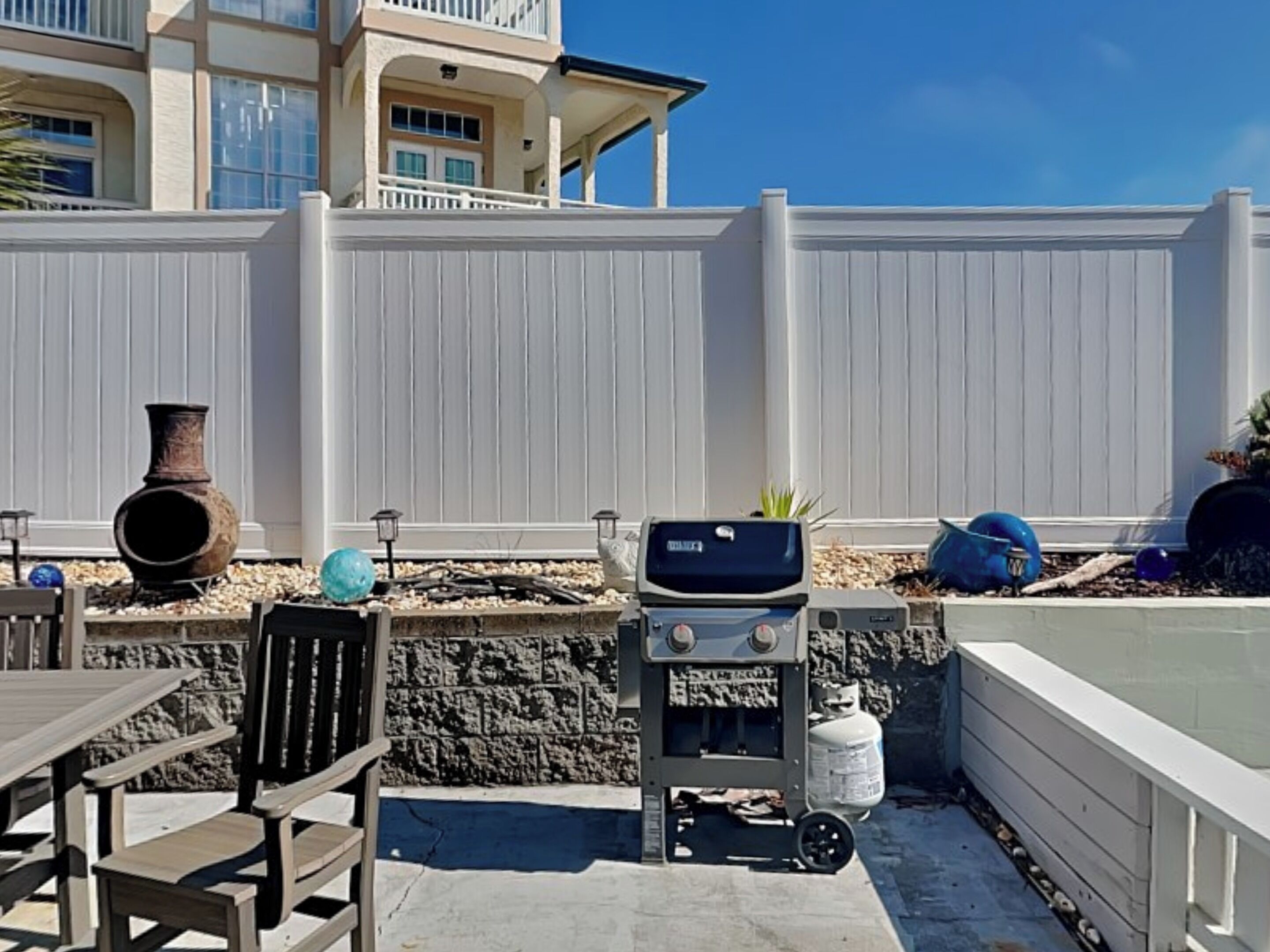 Une terrasse extérieure équipée d’un barbecue, de sièges et d’objets décoratifs.