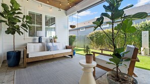Eine überdachte Terrasse mit einer Holzbank, Blumentöpfen und Lichterketten.