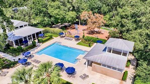 Ein großer Pool, umgeben von Sitzgelegenheiten im Freien und einer überdachten Terrasse.