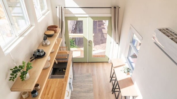 A compact, modern kitchen with a wooden countertop, a built-in stove, and a ceiling fan.