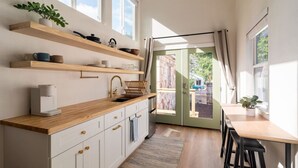 A modern kitchen with wooden shelves, a coffee maker, and a view to the outside.