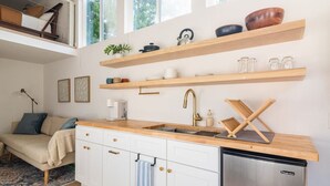 A modern kitchen with a wooden countertop, stainless steel appliances, and wooden shelves above the sink.