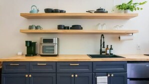Une cuisine avec des étagères en bois, une machine à café, un four et un évier.