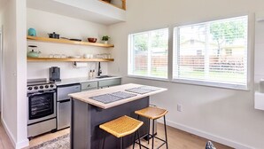 A modern kitchen with a central island, built-in oven, and bar stools. - Extended Stay Retreat: Cozy yet Spacious Tiny Gem! (Austin)