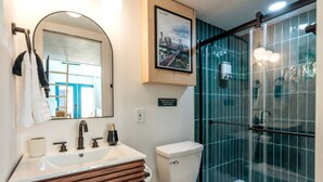 A modern bathroom with a vanity, toilet, and glass shower enclosure. - Cozy & Bright Mid-Century Gem in Eastside Action! (Austin)