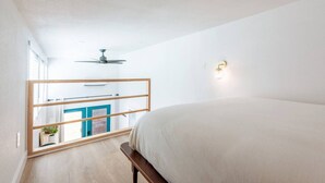A bedroom with a bed, a ceiling fan, a window with a view, and a wall-mounted light fixture. - Cozy & Bright Mid-Century Gem in Eastside Action! (Austin)
