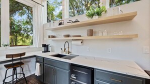 Una cocina moderna con un amplio ventanal, estanterías empotradas y un taburete de bar.