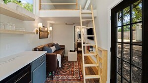 Una cocina compacta con lavavajillas integrado, una escalera de madera y un amplio ventanal.