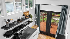 A compact kitchen with black countertops, a built-in stove, and a window overlooking a wooden deck.
