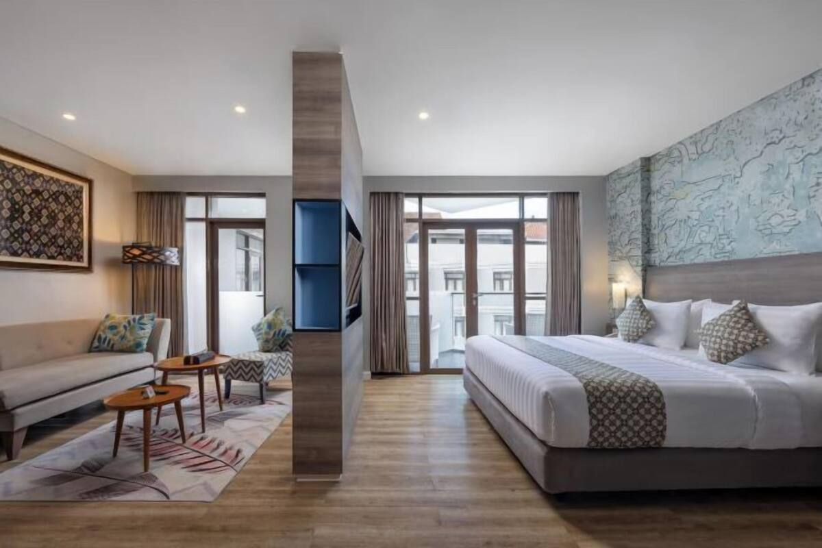 A modern hotel room with a large bed, a sofa, a small table, and a TV.