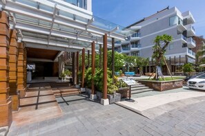 Ein Hotel mit Eingangsbereich, überdachtem Gang, Außenbereich zum Sitzen und Poolanlage.