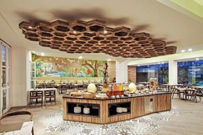 Ein Restaurant mit einer zentralen Insellounge, mehreren Sitzbereichen und einer Decke mit einem einzigartigen Holzkunstwerk.
