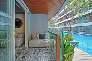 A balcony with a pool, a sofa with cushions, and a small table. - Wyndham Garden Kuta Beach Bali (Bali)