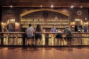 Eine Bar mit Ziegelwand, Barhocker und einer Theke, an der ein Barkeeper bedient.