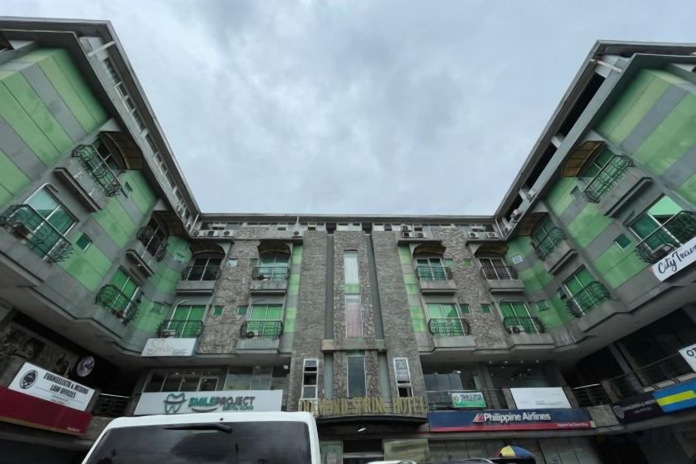 A multi-story building with a central atrium, multiple balconies, and various commercial establishments on the ground floor.