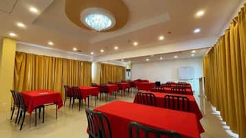 A conference room with multiple tables and chairs, a chandelier, and curtains.