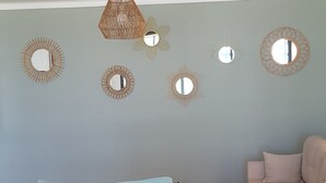 Una sala de estar con un sofá azul claro, un sillón blanco, una mesa de centro redonda y una alfombra estampada.