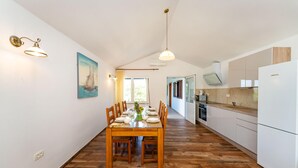 A spacious kitchen with a dining area, wooden flooring, and a painting of a sailboat. - Beautiful apartment in Seline with WiFi (Seline)