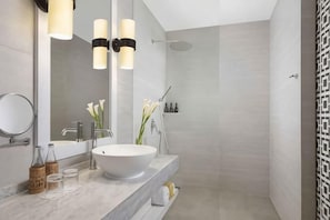 Une salle de bain moderne avec un grand miroir, un lavabo sur colonne et une douche.