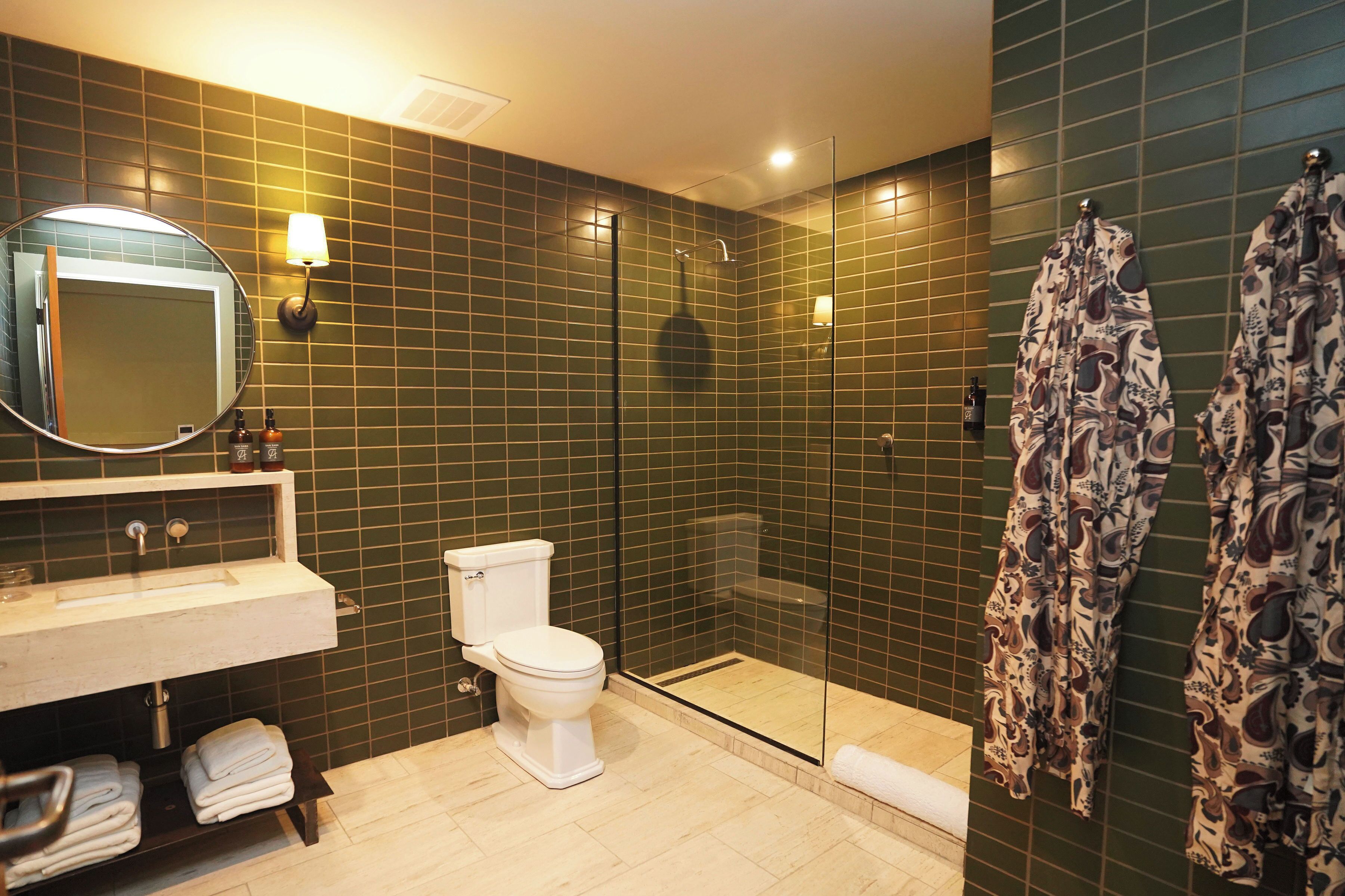 Une salle de bain comprenant des toilettes, un lavabo, un miroir et un espace douche.