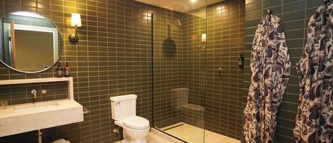 Une salle de bain comprenant des toilettes, un lavabo, un miroir et un espace douche.