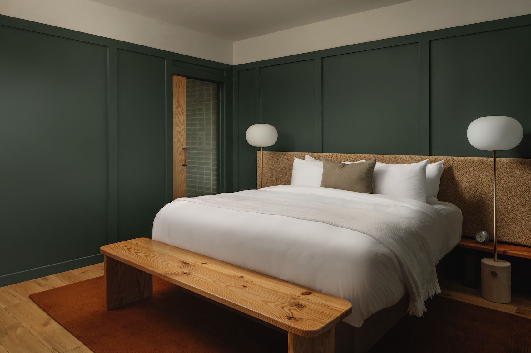 A bedroom with a bed, bench, bedside tables, and a nightstand.