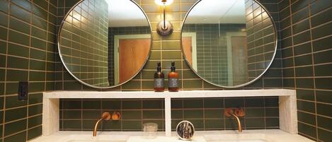A bathroom with two round mirrors, a light fixture above, and a sink with two faucets.