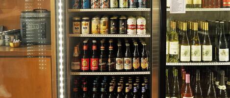 A beverage refrigerator stocked with various drinks including beer, wine, and canned beverages.