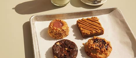 A table with a tray of cookies, a green drink, and a cup of coffee.