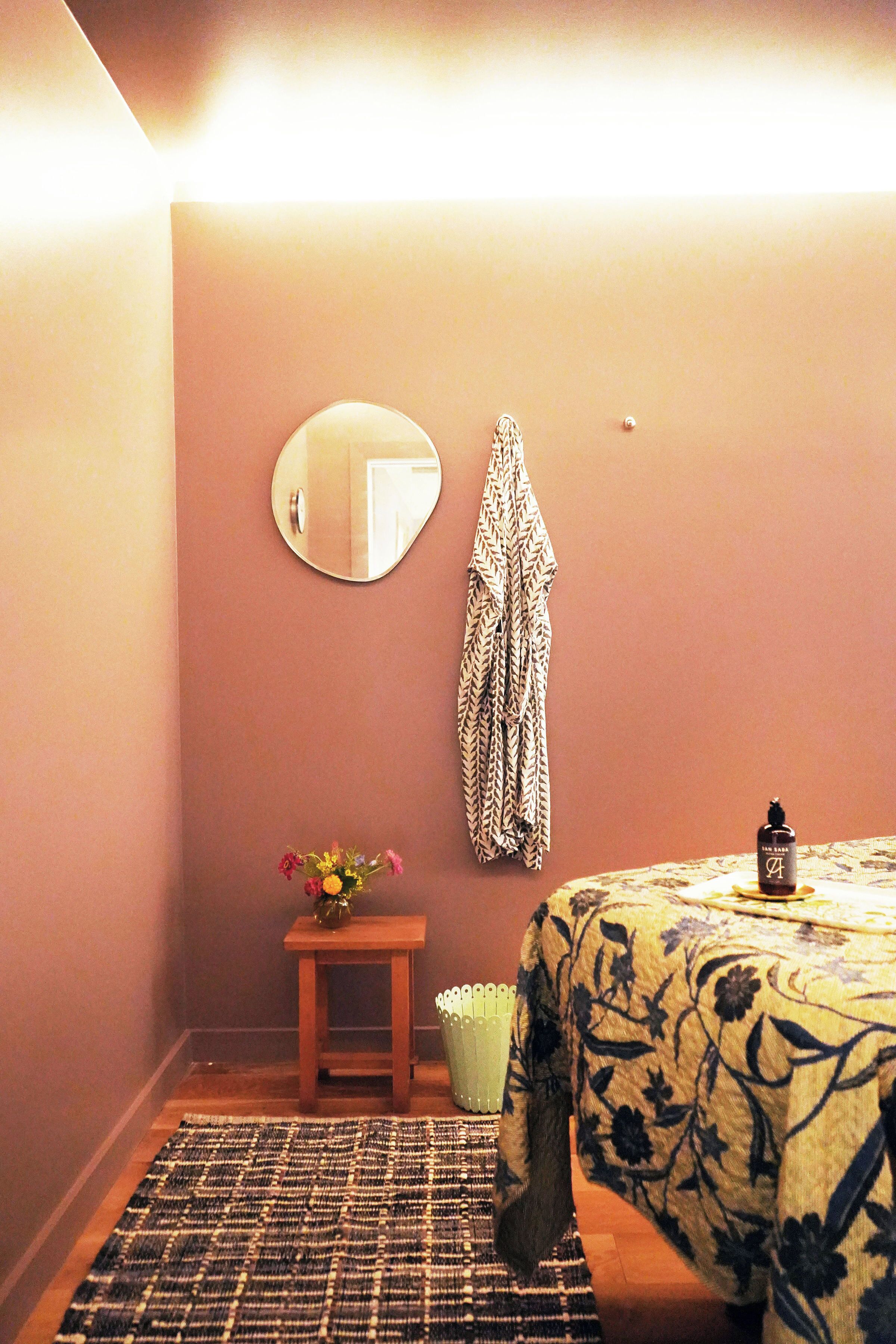 Un dormitorio con cama, mesita de noche, espejo y toalla colgada.