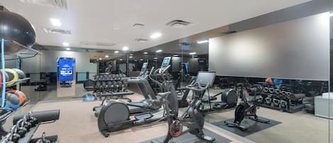 A modern gym with various exercise equipment, including treadmills, stationary bikes, and free weights.
