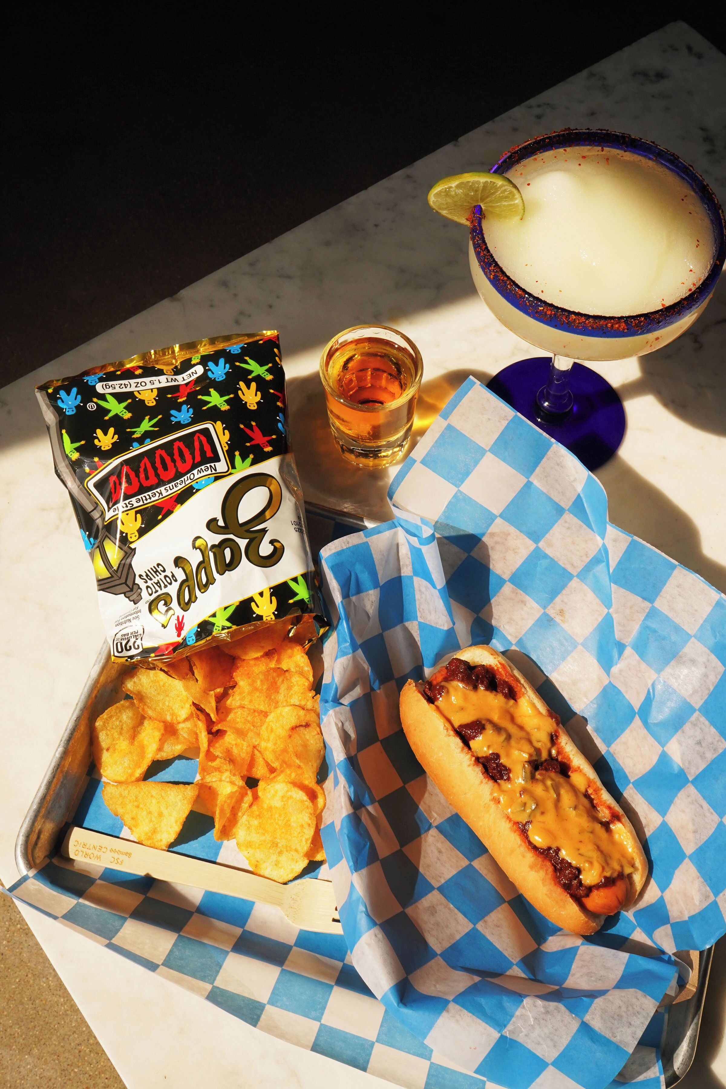 Et måltid med nachos, hotdog og margarita på et bord.