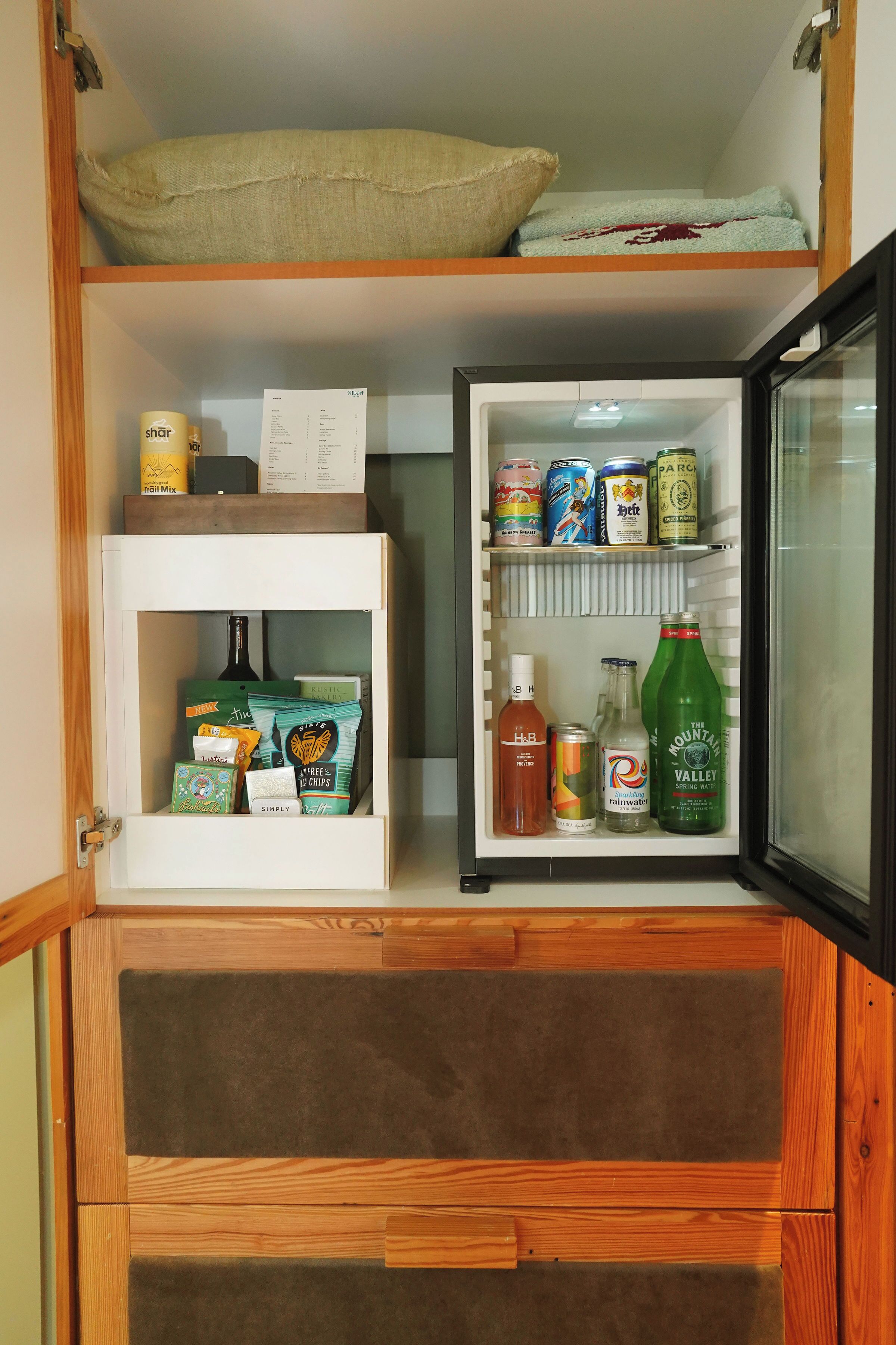 A compact kitchen with a refrigerator, a pantry, and a wooden cabinet.