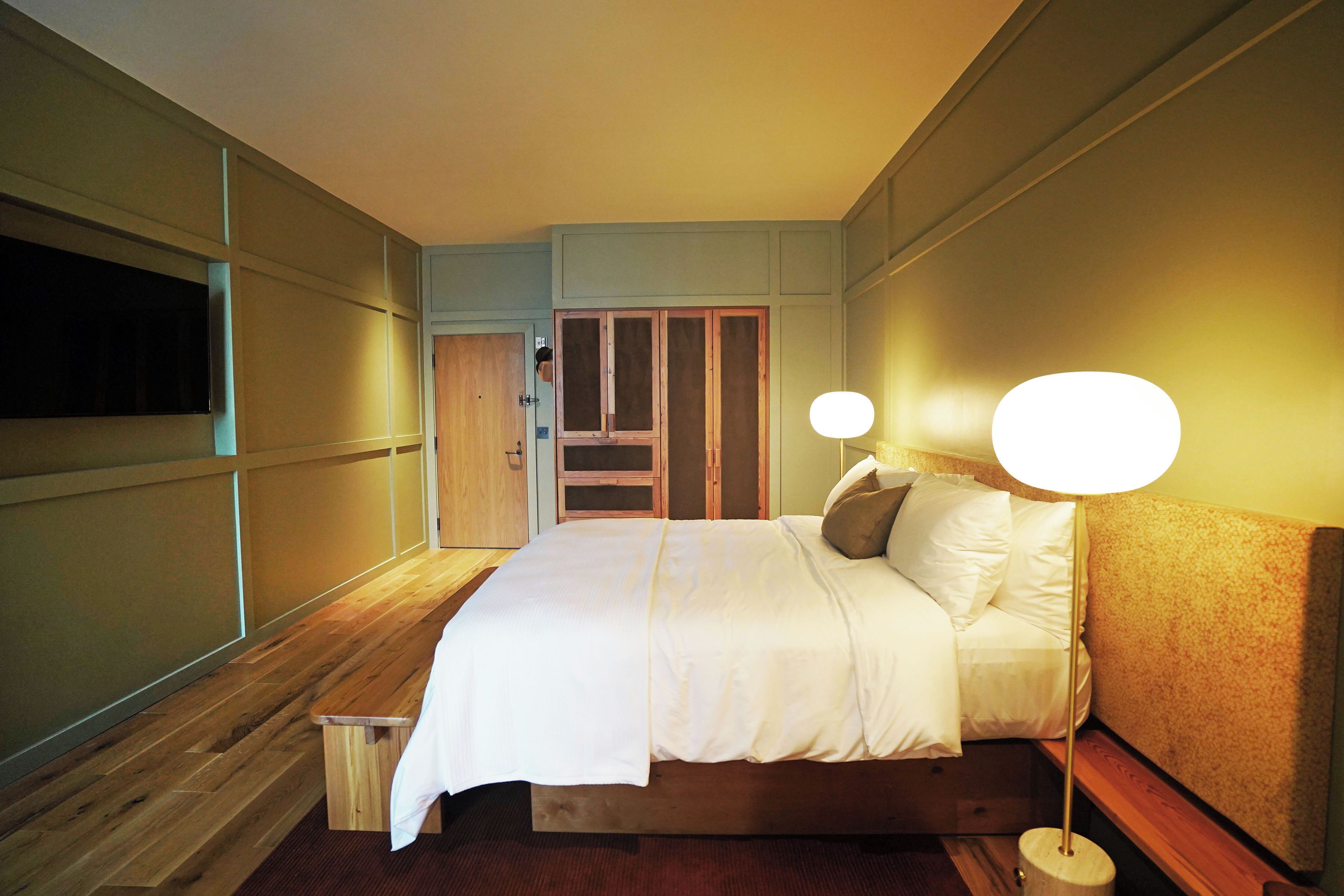 Un dormitorio ordenado con cama, mesitas de noche y lámpara.