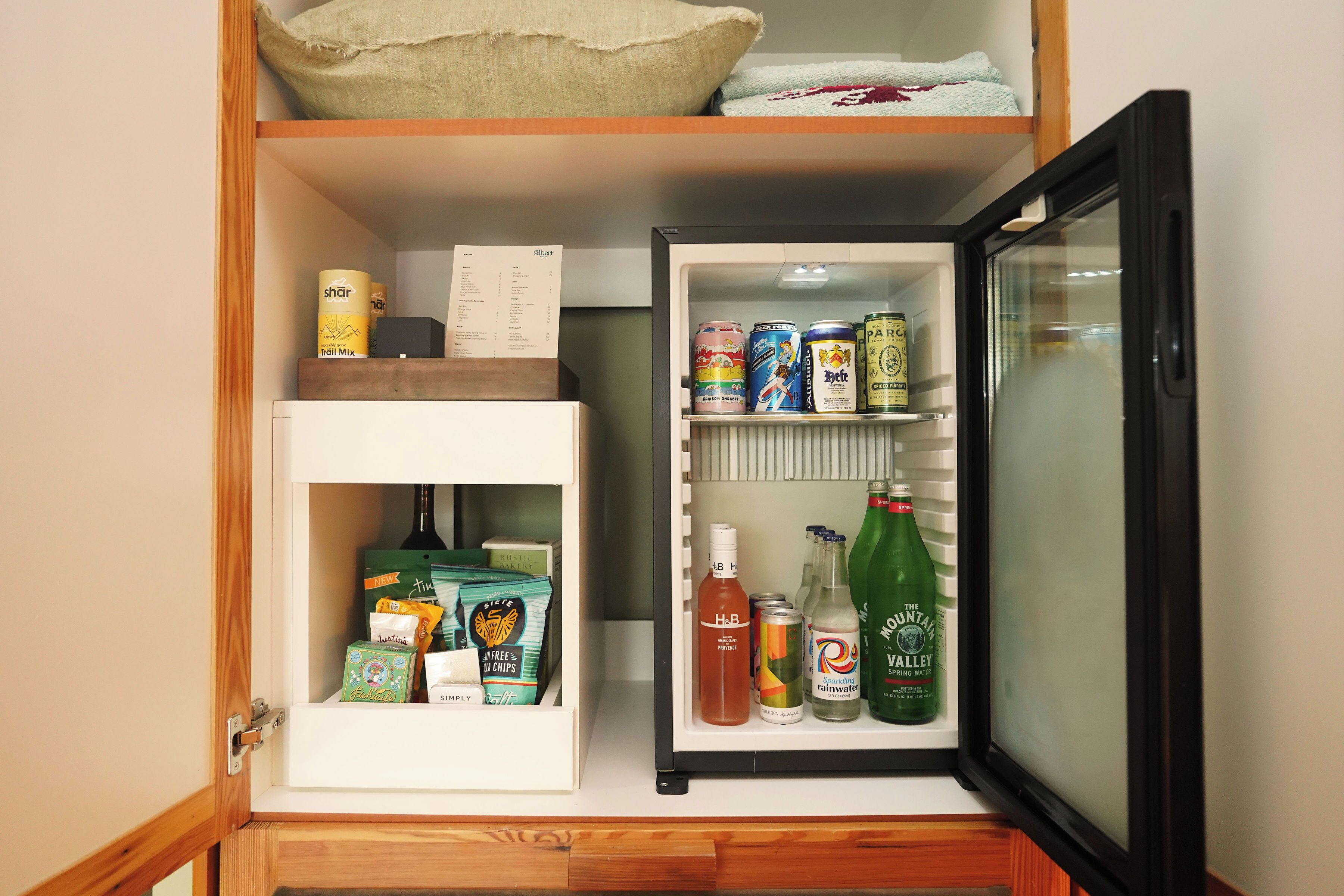 Ein kompakter Kühlschrank mit einem Gefrierfach oben, gefüllt mit verschiedenen Lebensmitteln und Getränken.