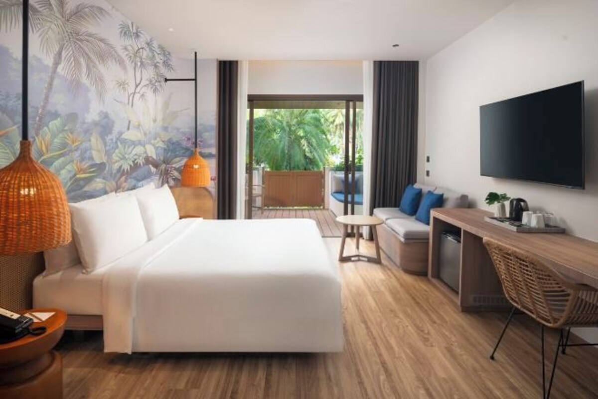 Habitación de hotel moderna con una cama grande, un escritorio, un televisor y vistas a zonas verdes.