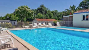 A rectangular swimming pool with clear blue water, surrounded by a metal fence. There are several white lounge chairs aligned along the pool's edge. - Awesome (sta)caravan in Saint-Georges-de-Didon (Saint-Georges-de-Didon)