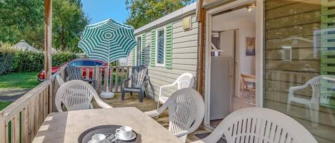 A covered patio with a table set for two, outdoor chairs, and a car parked in the background.