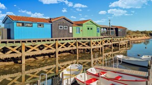 A row of colorful wooden buildings with a wooden pier extending into calm water, where boats are docked. - Awesome (sta)caravan in Saint-Georges-de-Didon (Saint-Georges-de-Didon)
