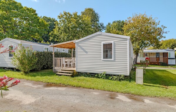 A mobile home with a porch, a small deck, and a window.